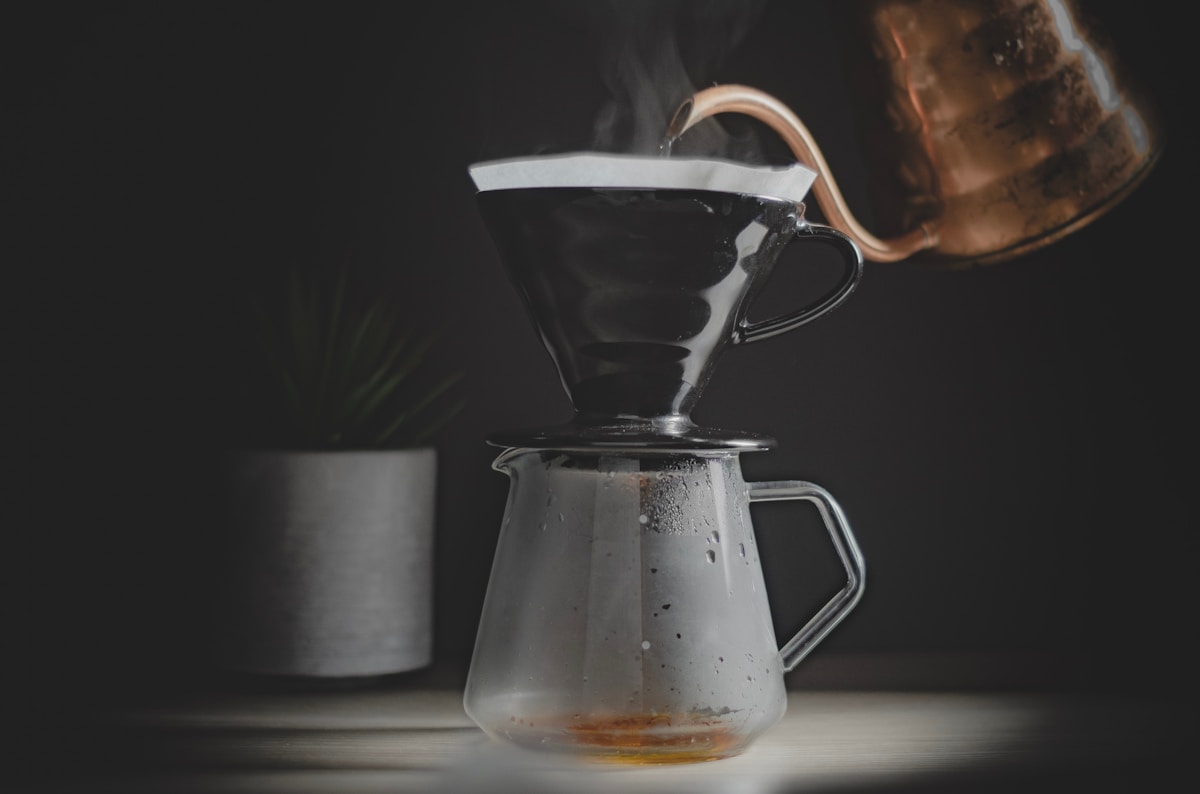 Hot water being poured from a gooseneck kettle into a pour-over coffee dripper
